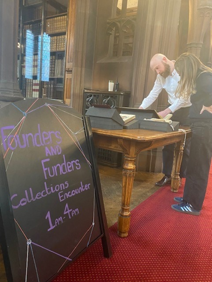 a man and a woman examining books and historical artefacts on a table