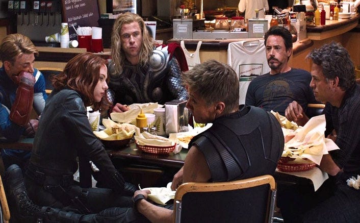 The Avengers sitting at a dining table and eating Taco Bell.