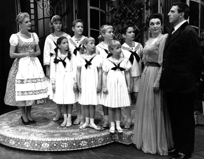 A cena mostra Capitão Von Trapp, Baronesa Schraeder, Maria e as crianças Von Trapp