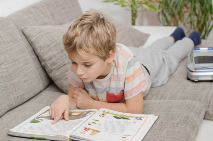 child reading children’s book on sofa