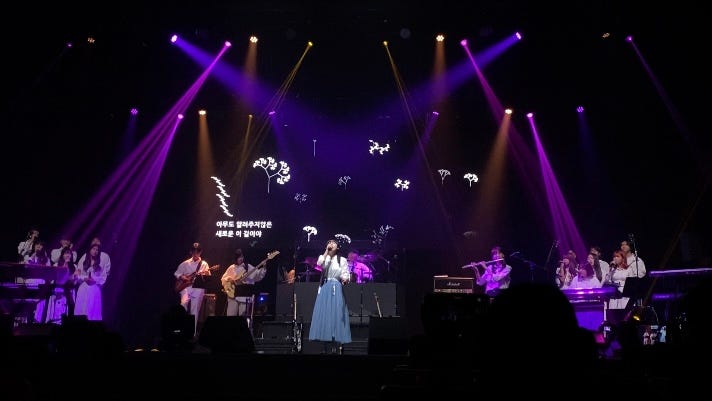 Similar as the previous one. The bright lighting points towards the vocalist. The projection shows L-system-looking small white tree graphics with various branches and shapes.