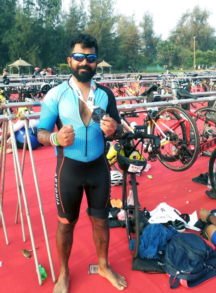 The writer after an Ironman triathlon, holding his finisher medal.