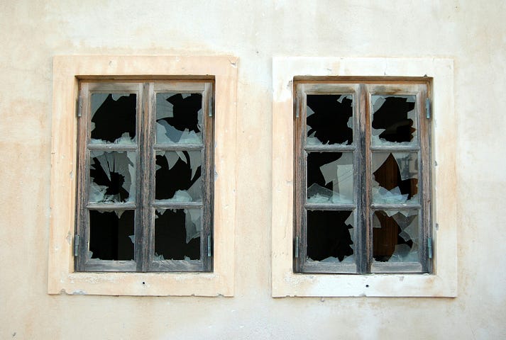 Two windows adjancent to each other, with broken glass.