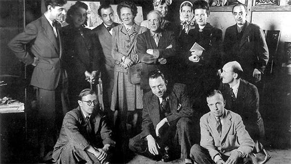 Una foto del 1944 del fotografo Brassaï che ritrae cast, durante una pausa delle prove, di Le Désir attrapé par la queue (Il desiderio preso per la coda) una pièce teatrale teatrale surrealista in sei atti scritta da Picasso durante l’occupazione nazista. In piedi da sinistra a destra: Jacques Lacan, Cécile Eluard, Pierre Reverdy, Louise Leiris, Zanie Aubier, Picasso, Valentine Hugo, Simone de Beauvoir (La Cousine). Seduti da sinistra a destra: Jean Paul Sartre, Albert Camus, Michel Leiris, Jean Aubier et Kazbek, il pastore afghano di Picasso. Non sono in questa foto Dora Maar , Germaine Hugnet , Raymond Queneau e Jacques Bost, anche loro nel cast della pièce. Una foto del 1944 del fotografo Brassaï che ritrae cast, durante una pausa delle prove, di Le Désir attrapé par la queue (Il desiderio preso per la coda) una pièce teatrale teatrale surrealista in sei atti scritta da Picasso durante l’occupazione nazista. In piedi da sinistra a destra: Jacques Lacan, Cécile Eluard, Pierre Reverdy, Louise Leiris, Zanie Aubier, Picasso, Valentine Hugo, Simone de Beauvoir (La Cousine). Seduti da sinistra a destra: Jean Paul Sartre, Albert Camus, Michel Leiris, Jean Aubier et Kazbek, il pastore afghano di Picasso. Non sono in questa foto Dora Maar , Germaine Hugnet , Raymond Queneau e Jacques Bost, anche loro nel cast della pièce.