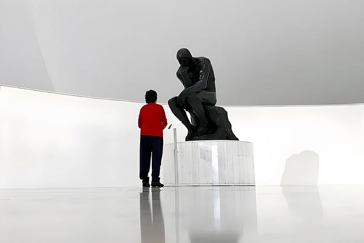 A woman looking at a statue of the thinker in a futuristic art gallery.