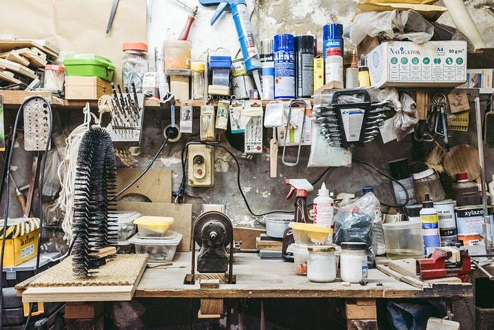 A cluttered workbench located in a messy garage.