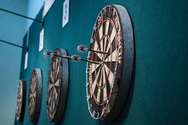 4 darts on a blue wall with arrows stuck on one of them.