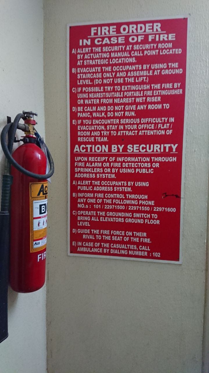 An emergency instructions poster and fire extinguisher that’s against the wall.