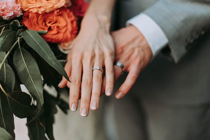 A couple pose their hands for a photo of the wedding rings on their wedding day.