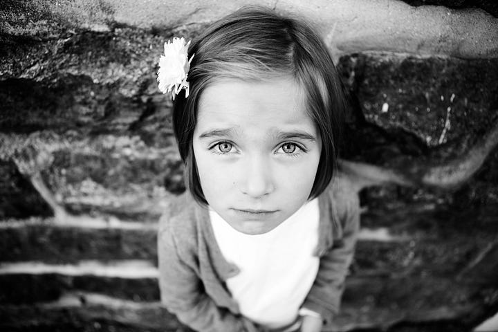 A scared little girl looking up into the camera with a worried look on her face.