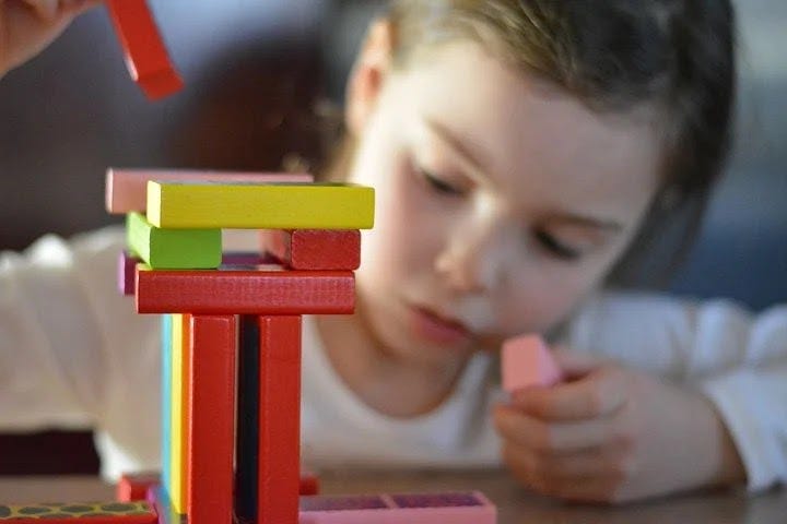 A girl playing with colorful building blocks.