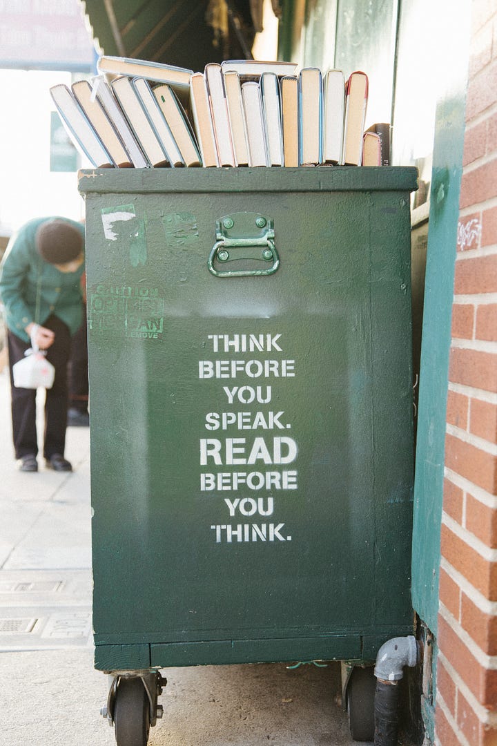 A green book cart has stenciled letters on the side which read,”Think before you Speak. Read before you think.