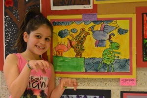 Selen Arkan, a second grader at DeMasi Elementary School, decided to have life imitate art as she posed like the dinosaurs behind her that she had created.