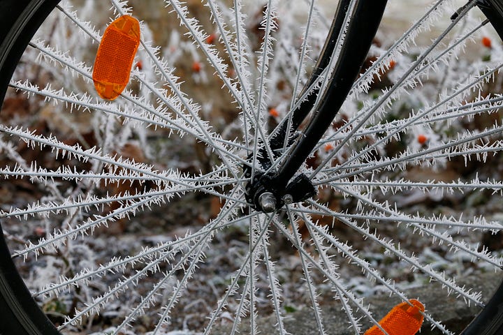 A bicyle wheel with frost on the spokes.