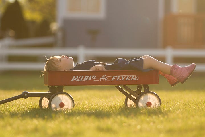 A child lying down in a radio flyer wagon