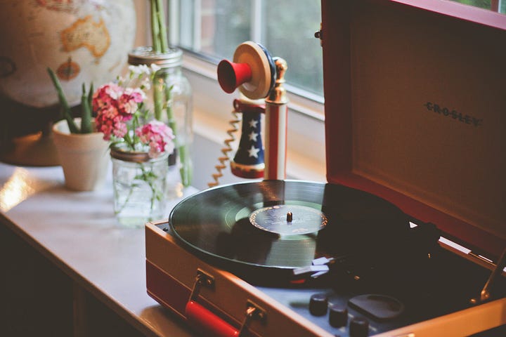 antique phonograph on window sill with antique phone and flowers