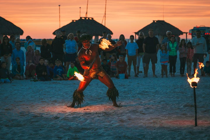 A man playing with fire at sunset on a beach.