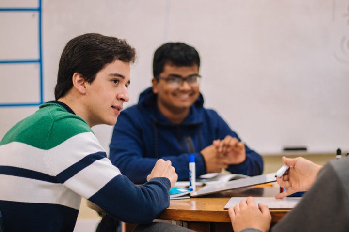 Classmate laughing and listening to other classmates