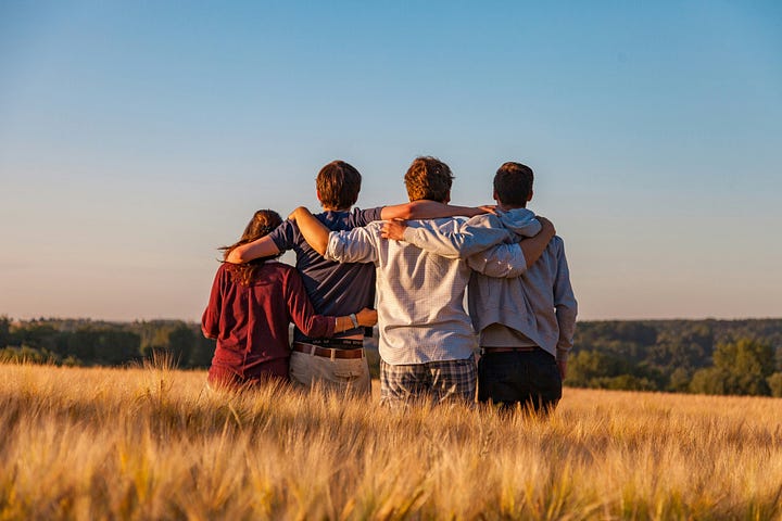 Photo of four teenage friends in a field of grass