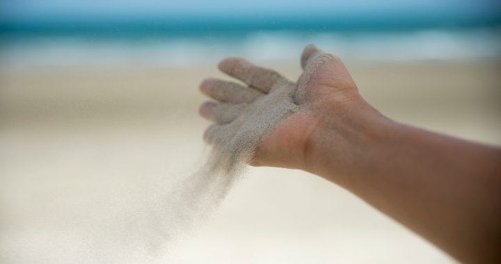 A handful of sand being released as we release our desires