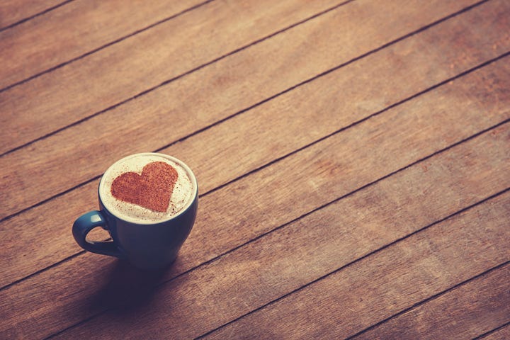 Cup of сoffee with shape heart on a wooden table.