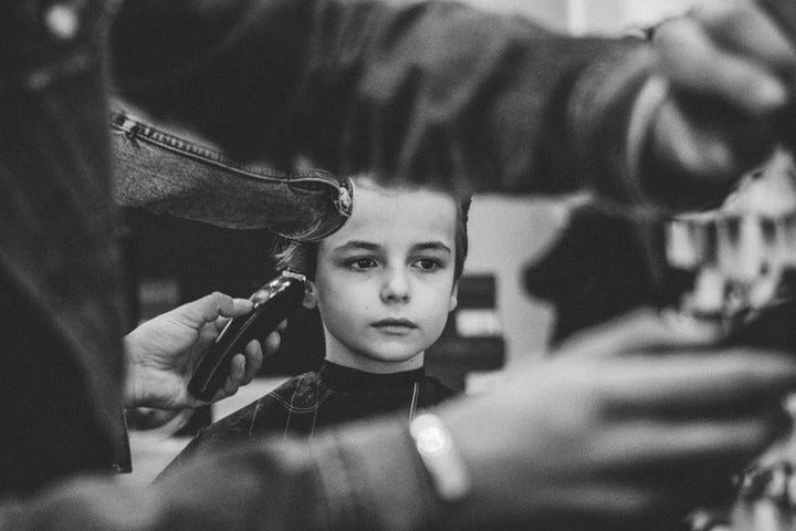 Young boy silent staring into space at the barber shop