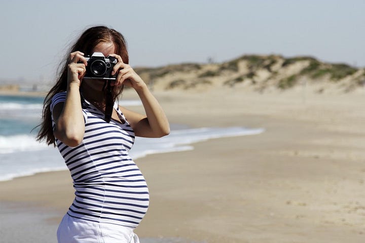 Pregnant Woman on Beach Taking Photos