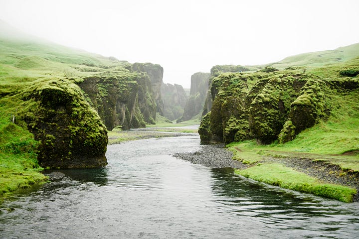 Green misty river gorge flowing softly to a white horizon.