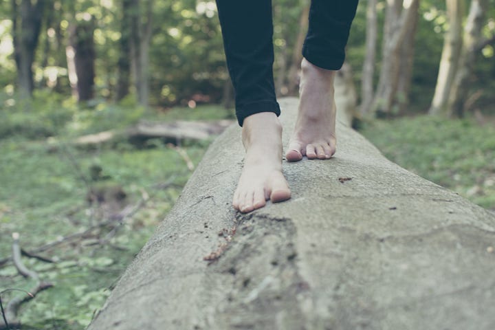 bare feet walking towards the camera, balancing on a log