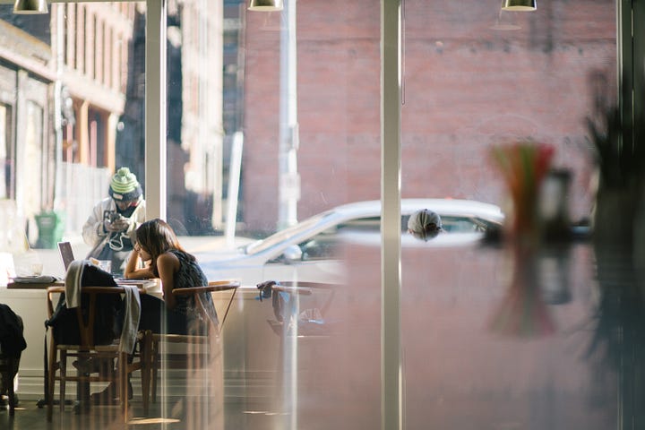 A woman sitting in a cafe whilst working away on her laptop.