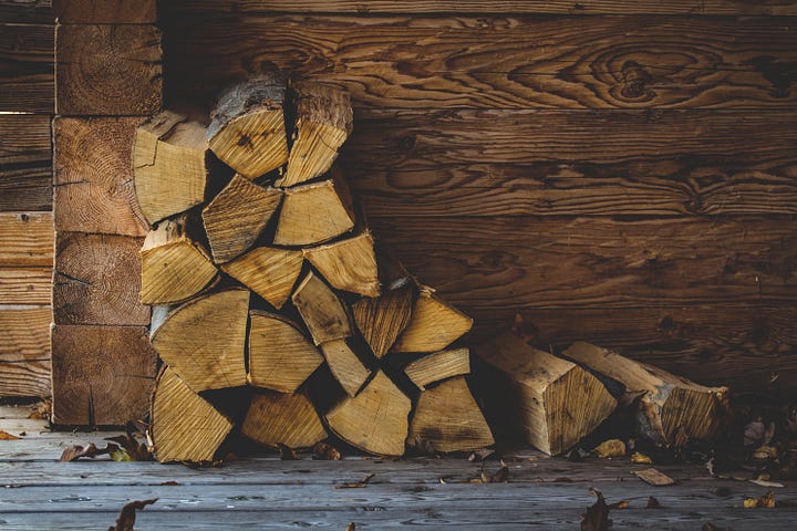 A small stack of chopped fire wood sitting against a wooden wall.
