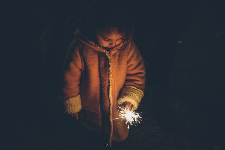 A young girl holding a sparkler at night