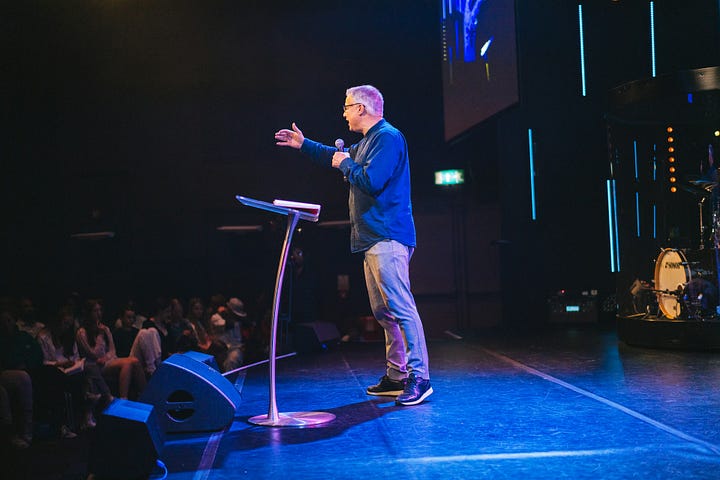 Spotlight on preacher ministering to the audience from a pulpit.