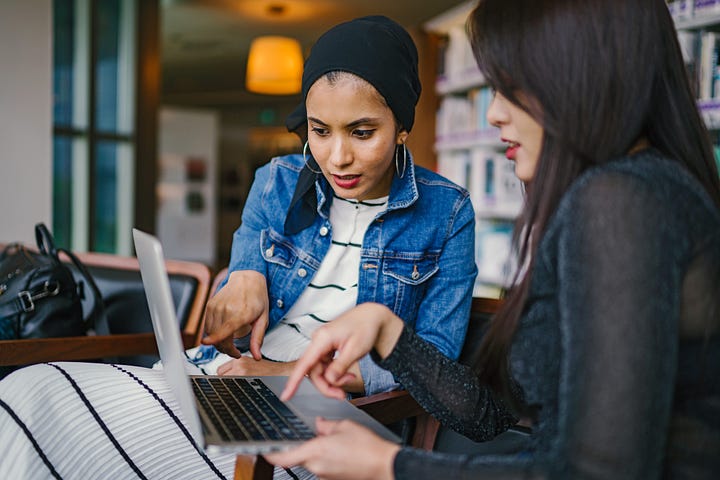 Two women pointing at a laptop