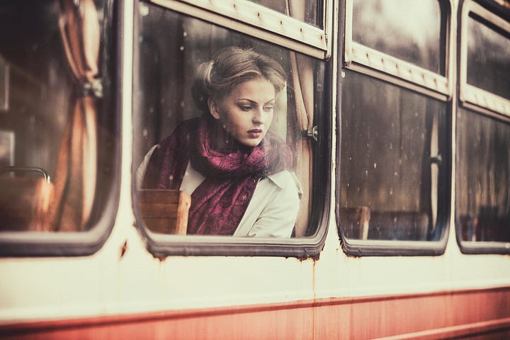 1950’s contemplative young woman looking out the window on vintage subway train