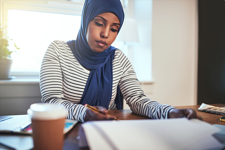 Focused young Muslim woman working at a home office.