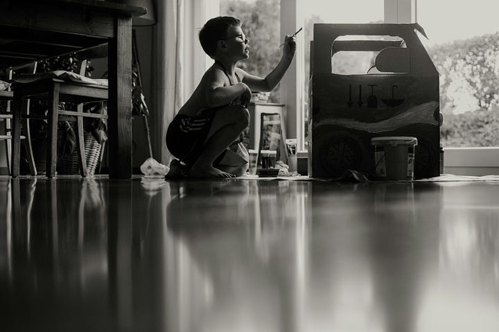 black and white photo of child sitting on the floor painting