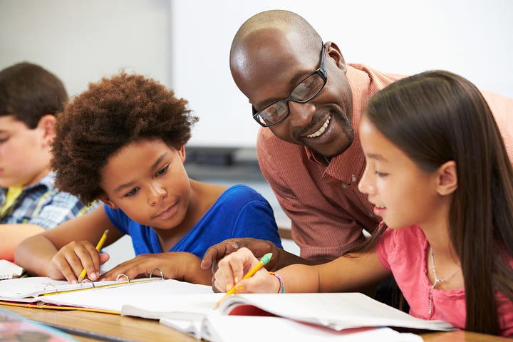 teacher engaging two students in reading and writing