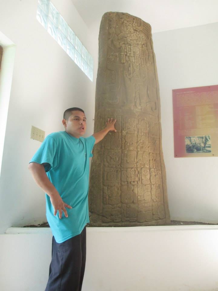 Museum tour guide has a hand on stone tablet that has drawings while he explains about Mayan communication.