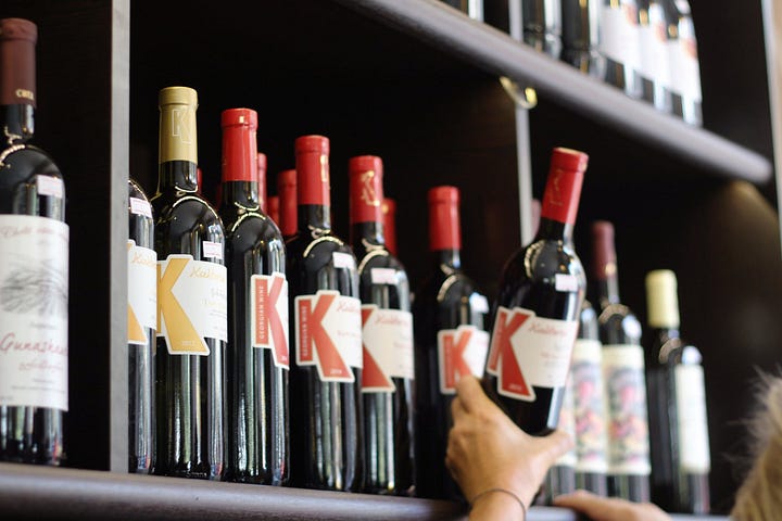 Customer reaching for wine bottle on shelf.