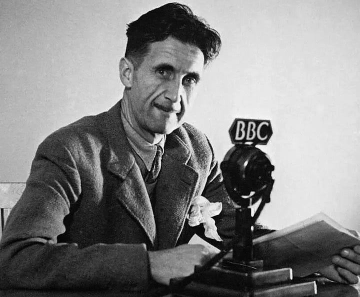 A black-and-white photo of George Orwell sitting in front of a BBC microphone