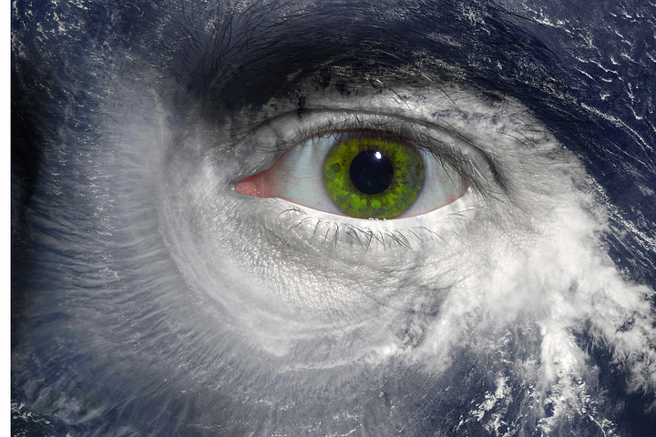 A green, human eye in the center with hurricane swirl around it