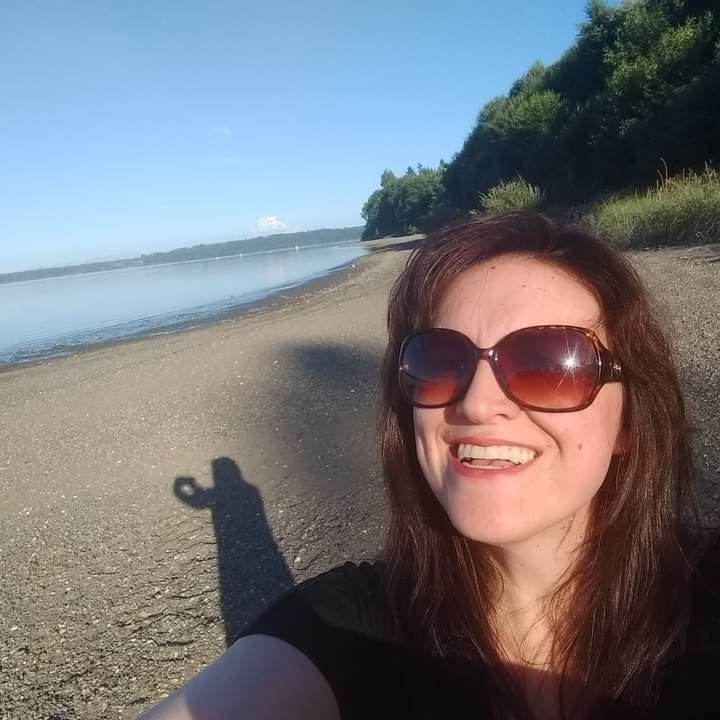 Social Equity Case Manager Sarah Davis in brown sunglasses taking a selfie at the beach