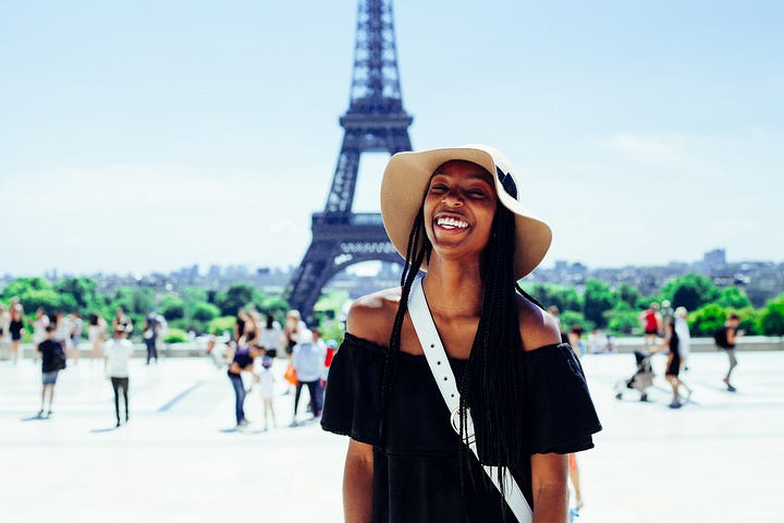 A woman smiling in Paris. She could be having an excellent Sunday.