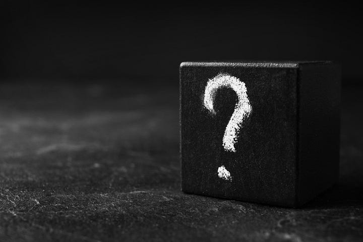 A wooden cube with a question mark on a table