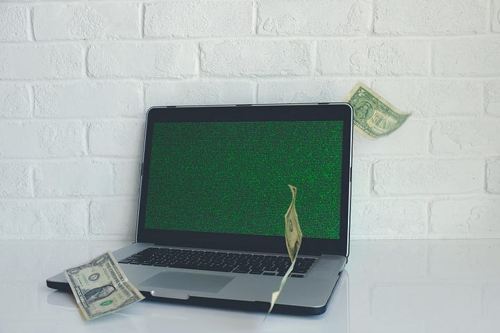 Dollar bills next to a broken laptop