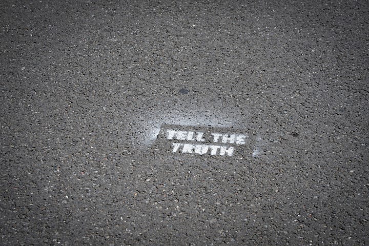 A road with the words tell the truth in spray paint written on it