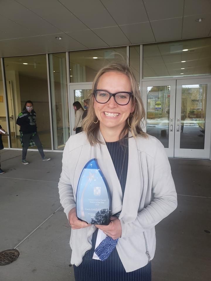 Carrie Syvertsen holds her award in front of Robert Eagle Staff Middle School