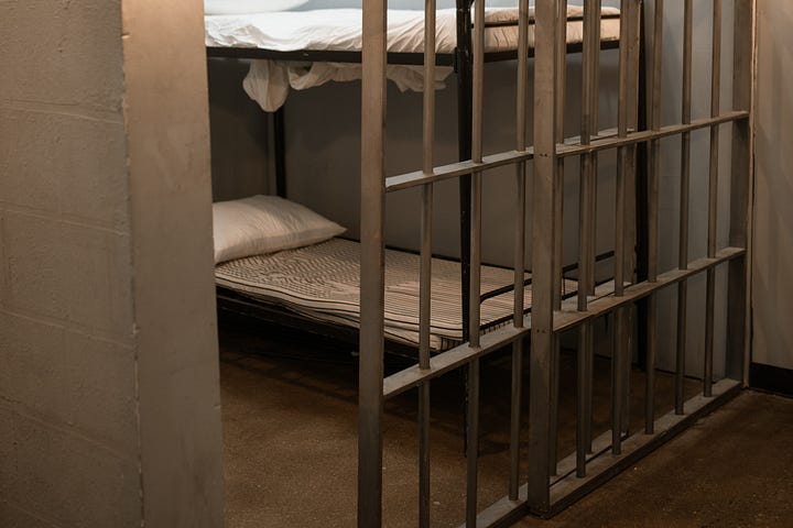 A prison cell with two bunk beds and doors with bars.