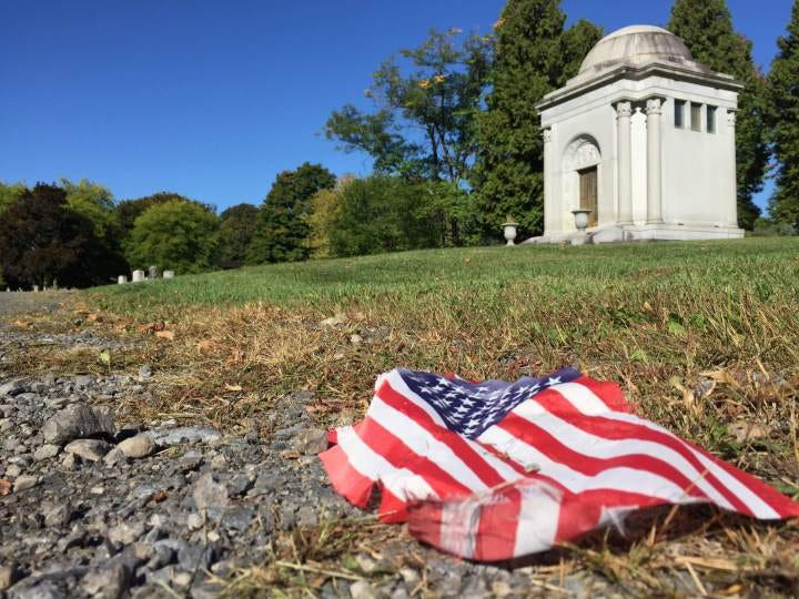 Crumpled American flag on grass in front of Oakwood Cemetery.